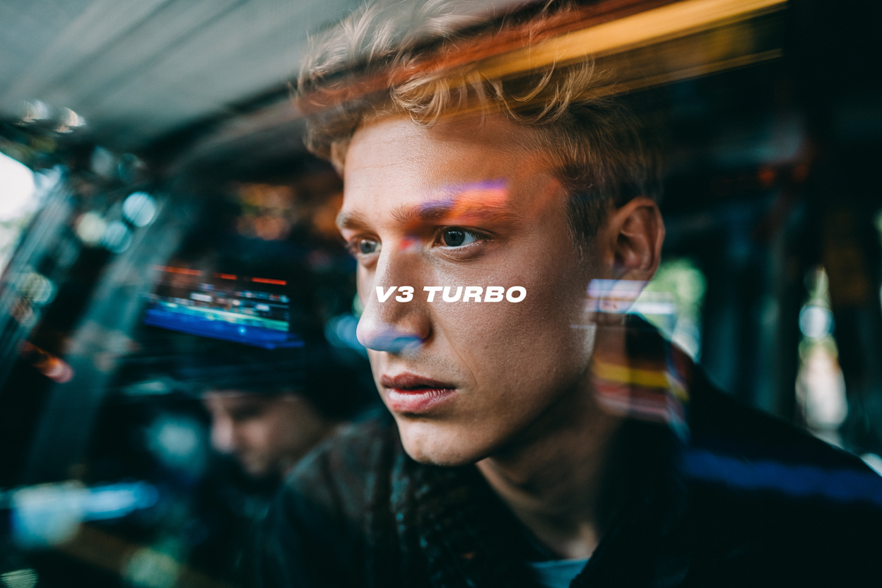 The text 'V3 Turbo' in the center middle. A color film-inspired portrait of a young man looking to the side with a shallow depth of field that blurs the surrounding elements, drawing attention to his eye. The fine grain and cast suggest a high ISO film stock, while the wide aperture lens creates a motion blur effect, enhancing the candid and natural documentary style.